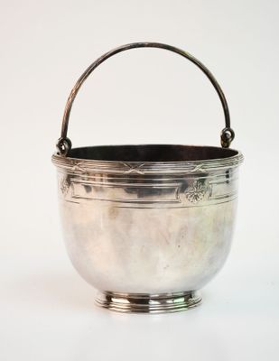 un bol ancien plaqué argent muni d'une anse, sur fond blanc