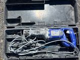 a blue electric drill in a black case on the ground