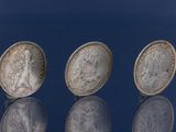 trois pièces d'argent empilées les unes sur les autres sur une surface bleue
