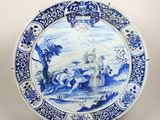 assiette bleue et blanche ornée d'une peinture représentant un homme et une femme dans un paysage