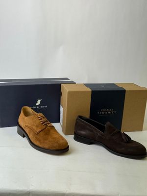 three pairs of men ' s shoes sitting on a table next to a box