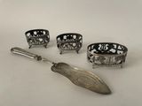 four pieces of silverware including a spoon, spoon and spoon rest