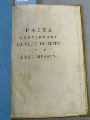 un vieux livre posé sur une table bleue, à côté d'un verre