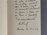 un livre ouvert, sur lequel est posée une note manuscrite, posé sur une table
