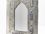 an ornate silver mirror with blue glass in the middle of it