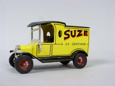un petit camion jouet jaune avec des roues rouges et des jantes rouges, posé sur une surface blanche