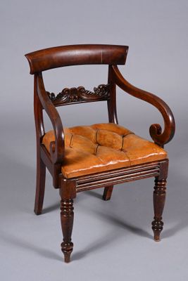 an antique wooden chair with a leather seat on a grey background