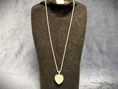 a necklace with a heart shaped pendant on a mannequin