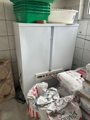 un réfrigérateur blanc dans un coin de la cuisine, sur lequel est posé un seau vert