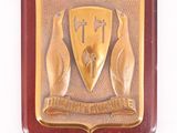 plaque représentant un bouclier sur lequel figure une main tenant une croix et un bouclier orné d'une croix