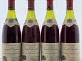 quatre bouteilles de vin sont alignées sur une surface blanche