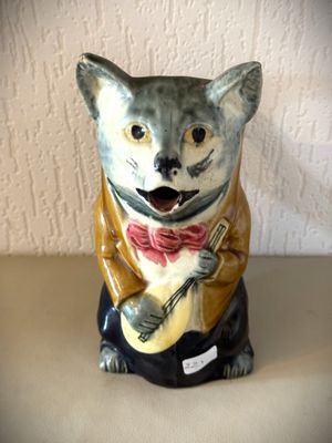 une figurine de chat portant un nœud papillon et jouant de la guitare