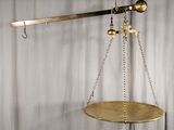 une balance en or dont pendent des chaînes de chaque côté