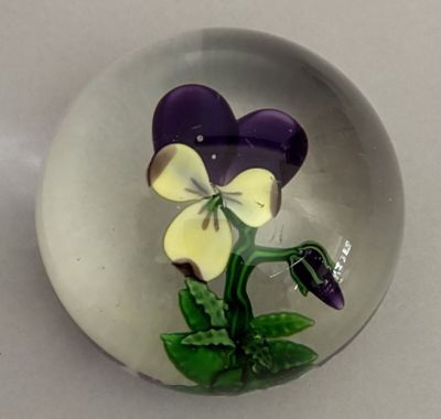 a glass bowl with a purple and white flower inside of it