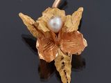 une broche en forme de fleur, en perles et en or, sur un fond noir