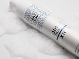 une image représentant un tube de produit capillaire posé sur une surface blanche