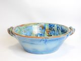 a blue and green bowl with handles on a white surface