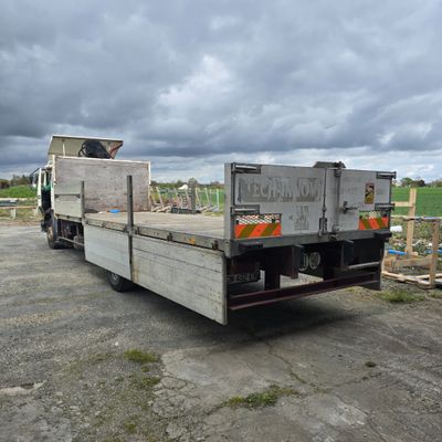 un camion garé sur un parking sous un ciel nuageux
