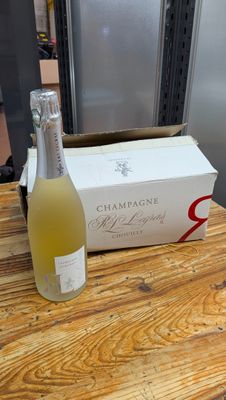 une bouteille de champagne posée sur une table à côté d'un carton de vin