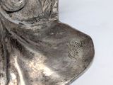 a silver statue of a woman with a hat on her head