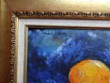 un tableau représentant une orange, dans un cadre doré, accroché à un mur rouge