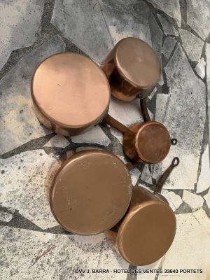 four copper pots and pans sitting on a marble floor
