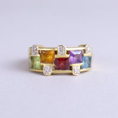 gros plan d'une bague en or avec des pierres multicolores