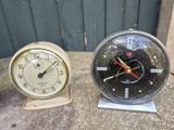 two clocks sitting next to each other on a table
