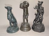 trois statues en bronze représentant un homme et un chien, posées sur un socle