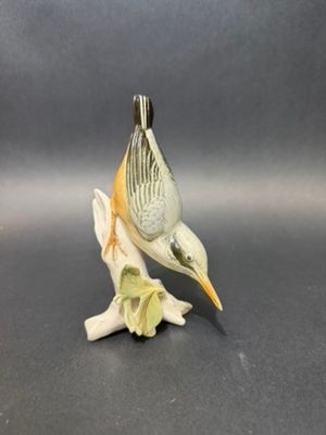 porcelain figurine of a bird on a branch on a gray background