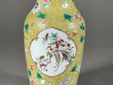 vase jaune orné de fleurs et d'oiseaux peints sur un fond gris