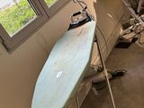 an image of a room with a surfboard and ironing board