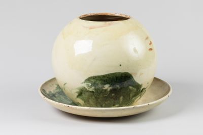 un vase blanc et vert posé sur une soucoupe, lui-même posé sur une soucoupe