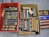 Plusieurs cartons remplis de vieux livres sont posés les uns à côté des autres sur le sol.