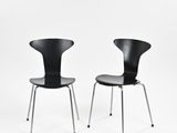 une paire de chaises noires sur fond blanc, avec une toile de fond blanche