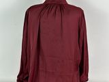 a woman ' s burgundy blouse with gathered neckline and long sleeves