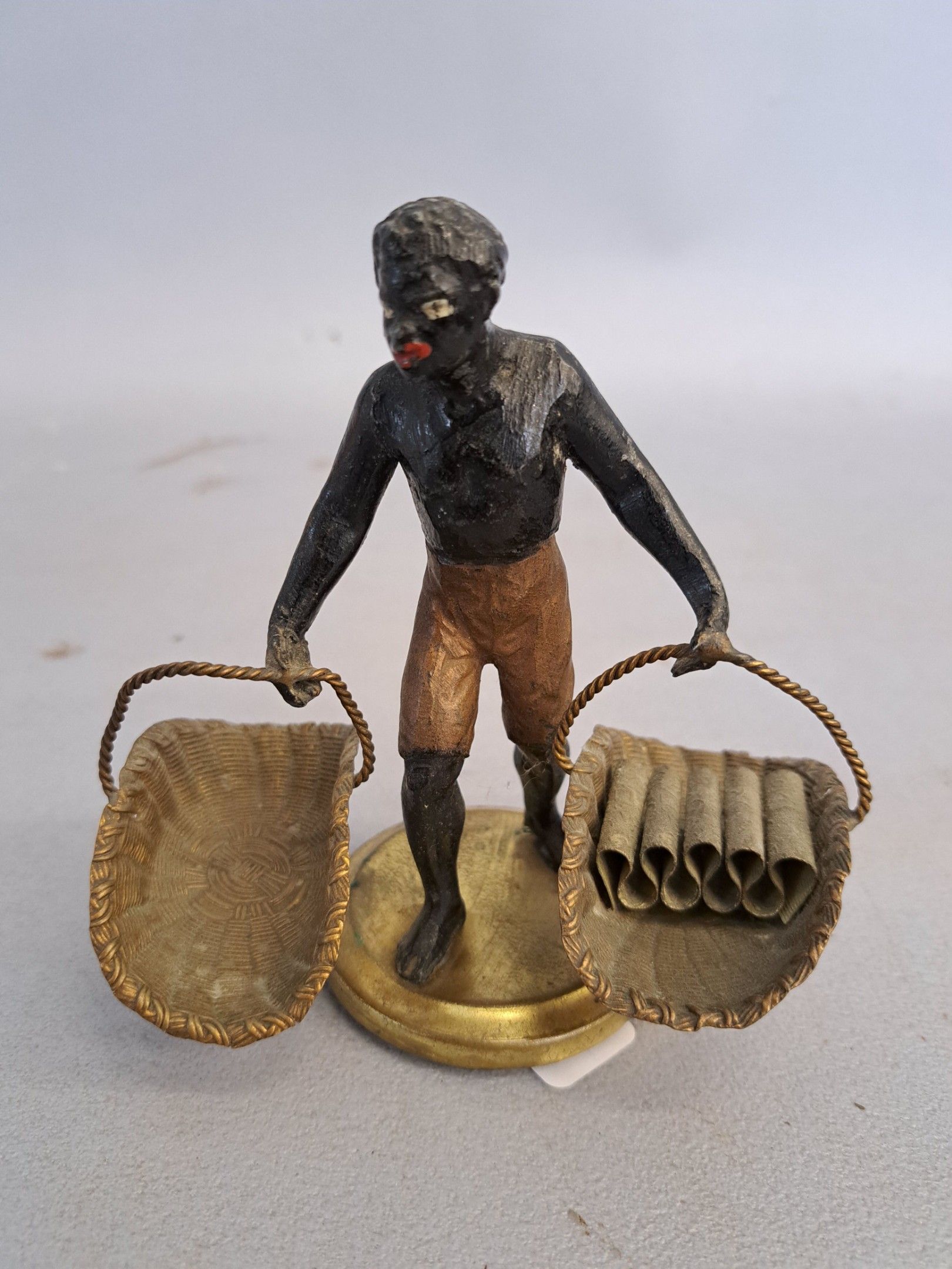 Le Porteur, sujet en métal peint polychrome à décor d'un homme portant deux paniers. H. : 12,5 cm.