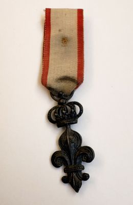 une vieille médaille à laquelle est accroché un ruban rouge sur le côté