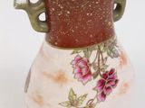 a vase that has a handle on it with flowers on it