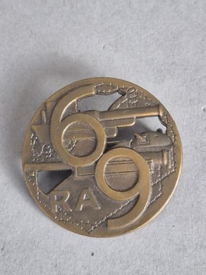 une pièce de monnaie sur laquelle est représenté un pistolet, posée sur une surface blanche