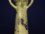 un vase vert à deux anses sur fond bleu foncé