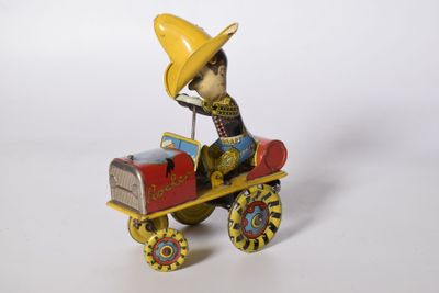 figurine représentant un homme coiffé d'un chapeau jaune au volant d'une petite voiture