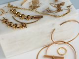 des bijoux en or posés sur un bloc de marbre, avec un mur bleu en arrière-plan