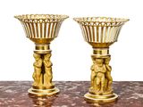 two gold vases sitting on a table with a white background