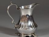 a silver pitcher sitting on a stand on a table