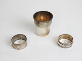 deux coupes en argent et une bague en argent posées sur une surface blanche