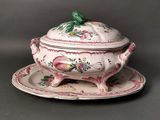 a white and pink tureeny dish with a green bird on top