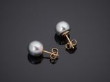 a pair of pearl earrings on a black surface