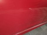 the door of a red car with the door handle missing
