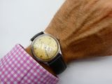 a man wearing a watch on his wrist with a pink checkered shirt